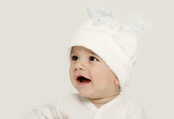 Innocent baby wearing a white bunny hat looking adorable.