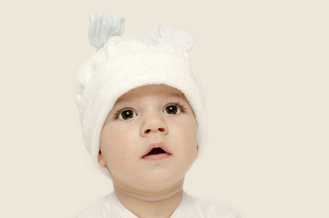 Innocent baby wearing a white bunny hat looking adorable.