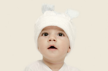 Innocent baby wearing a white bunny hat looking adorable.