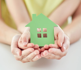 close up of woman and girl hands with paper house