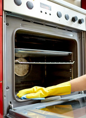close up of woman cleaning oven at home kitchen