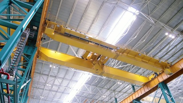 Factory crane moves on top of a large workshop