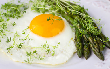 Breakfast of fried eggs, asparagus and watercress salad