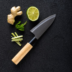 Knife and food ingredients on black stone table top view