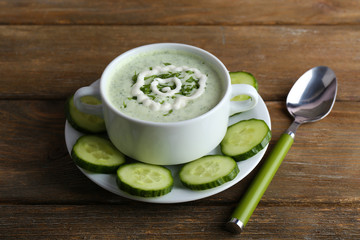Cucumber soup in bowl on rustic wooden table background