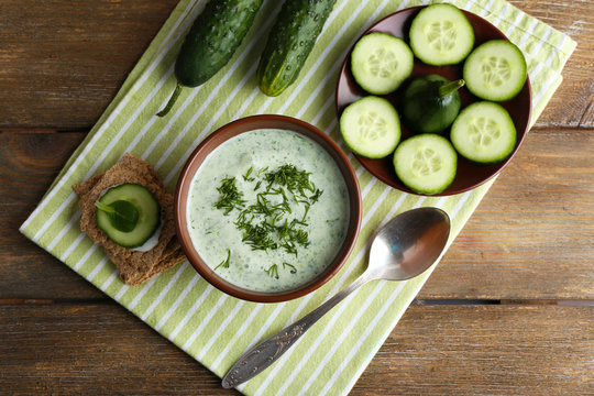 Cucumber soup in bowl on rustic wooden table background