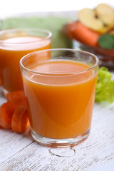 Glasses of juice with apple and carrot on wooden table close up