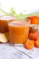 Glasses of juice with apple and carrot on wooden table close up