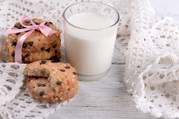 Tasty cookies and glass of milk on color wooden background