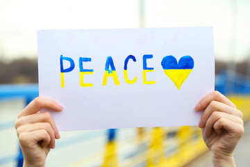Hands holding paper with Peace of Ukraine
