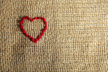 Linen canvas with red heart embroidered on it, close-up