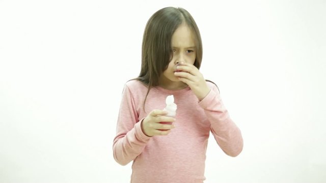 Young girl taking medicine in syrup form and making expressions