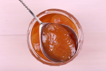 Jar of tasty jam on wooden background