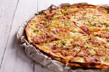 Tasty pizza on paper on wooden background