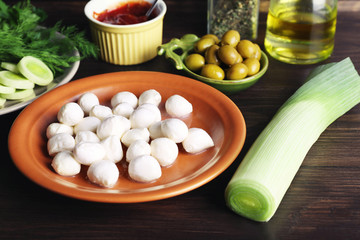 Mozzarella cheese with olives and greens on wooden background