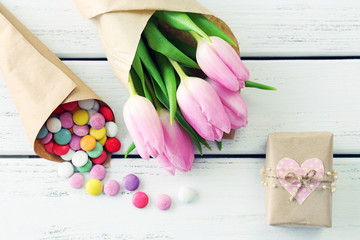 Beautiful pink tulips in paper with sweets and present box