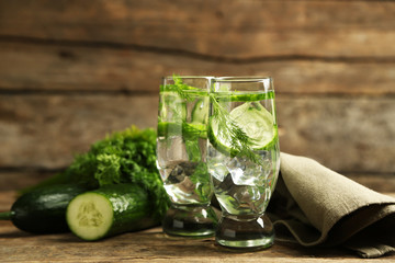 Glasses with fresh organic cucumber water on wooden table