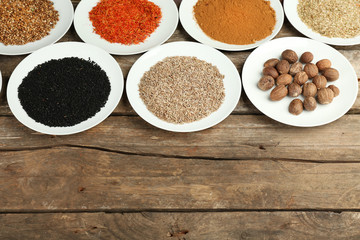 Different spices on plates, on old wooden table