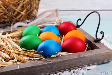 Easter eggs  on wooden tray, on colorful background
