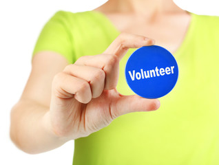 Round volunteer button in hand of girl isolated on white