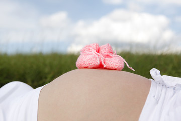 Pregnant woman with pink baby shoes on her belly