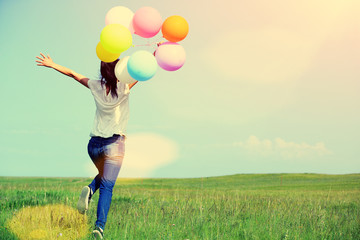 young asian woman on green grassland with colored balloons 