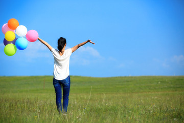 young asian woman on green grassland with colored balloons 