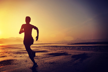 young woman running on sunrise beach  