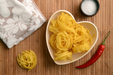 Raw tagliatelle in a heart shaped bowl