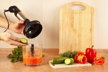 Hands chefs put chopped cucumber in a blender