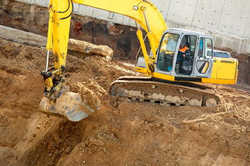 Excavator with metal tracks loading soil at construction site