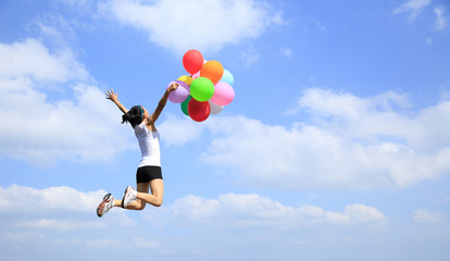 young asian woman mountain peak jumping with colored balloons 