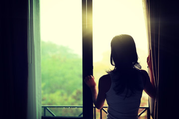 girl opening curtains in a bedroom