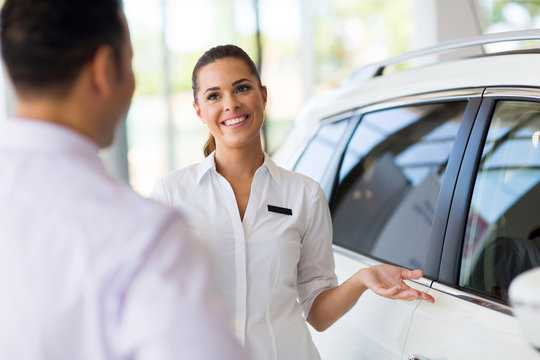 saleswoman showing new car to a customer