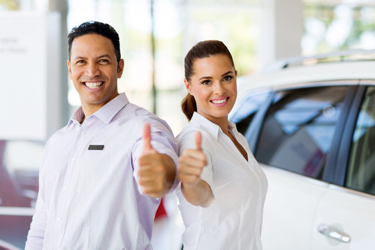sales staff with thumbs up at a car dealership