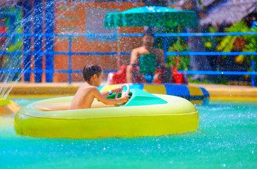 happy kid driving toy water boat in aqua park