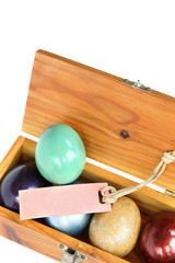 Colorful easter eggs in wood box on white background with paper