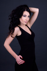 young beautiful sexy woman in black dress posing over grey
