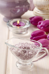 Glass jug of lavender sea salt on white wooden table