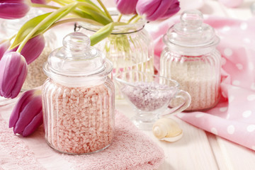 Glass jar of pink sea salt on white wooden table