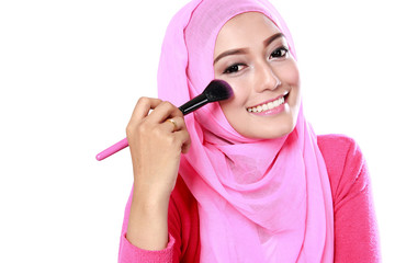 young muslim woman applying blush on