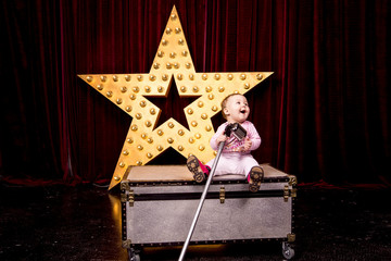 little girl sitting on the box and singing into a microphone