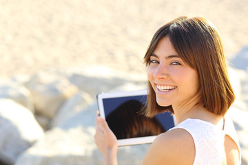 Fototapeta premium Woman using a tablet and looking at camera