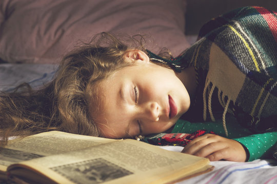 Toned portrait of cute school girl sleeping on the books
