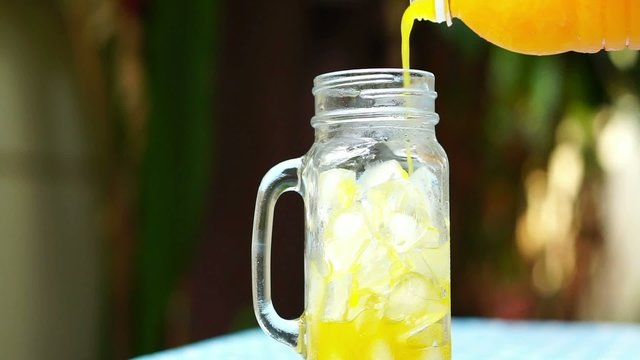 Pouring orange juice into a glass jar