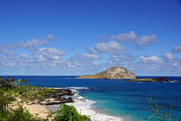 Makapuu beach with people in the water, and Rabbit and Rock Isla