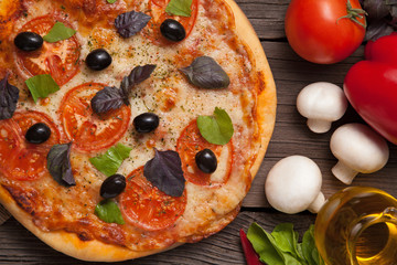 Pizza margherita with tomatoes, pepper, olives and basil on vint