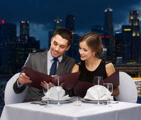 smiling couple with menus at restaurant