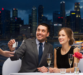 smiling couple paying for dinner with credit card