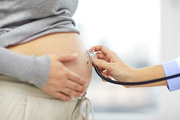 close up of pregnant woman belly and doctor hand